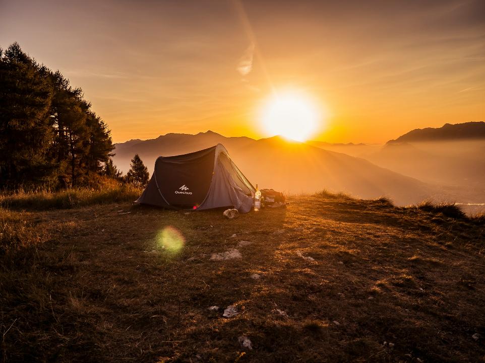 dome tent on mountain top with sun as background photo